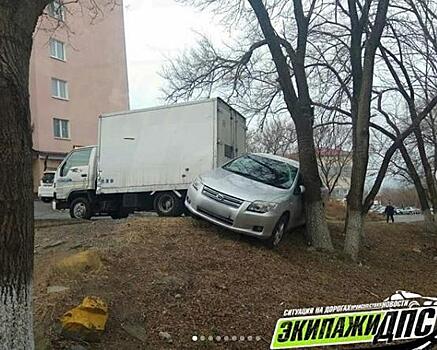 Во Владивостоке грузовик сорвался с ручника и прижал иномарку к дереву