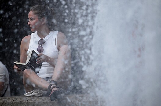 Девушка отдыхает у фонтана на Манежной площади в Москве, 26 июня 2022 года