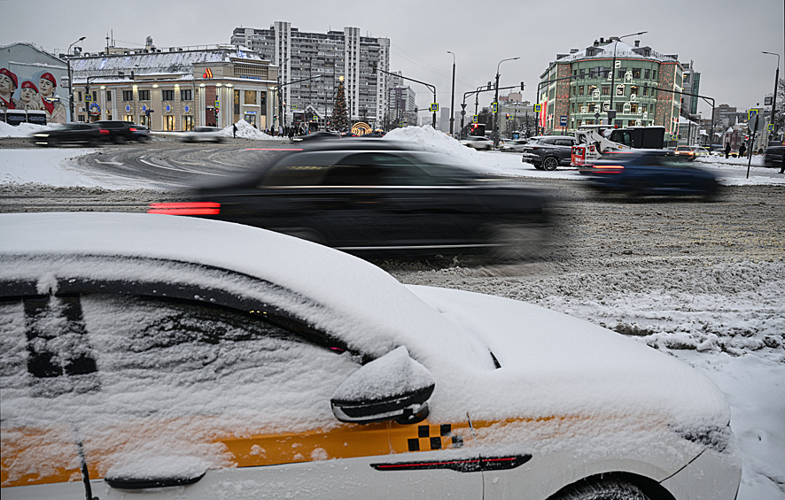 Заснеженный автомобиль такси у станции метро "Таганская" в Москве