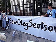 Украинские активисты машут плакатами с надписями «FREESENTSOV» перед окнами Посольства РФ в Киеве