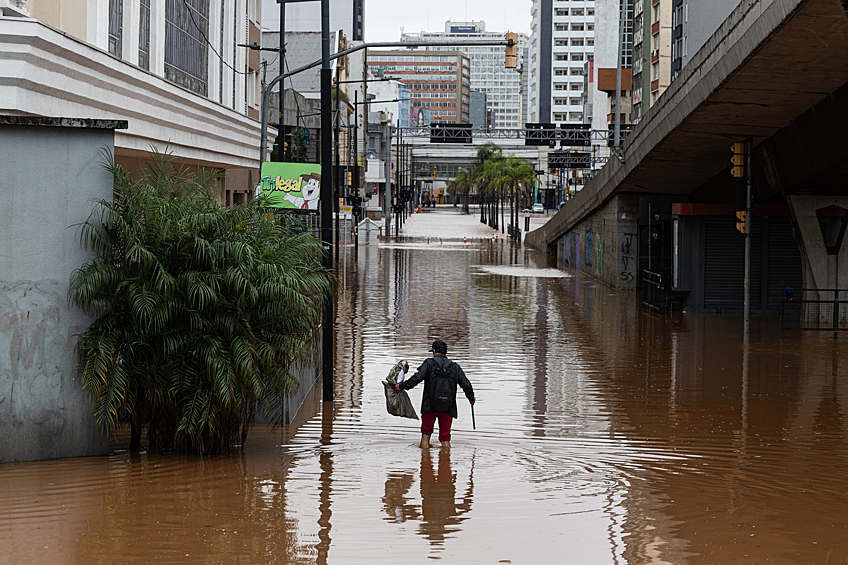 Мужчина идет по затопленной улице в центре Порту-Алегри