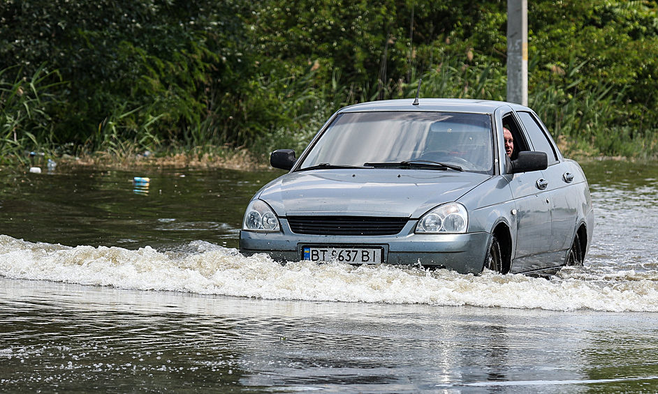 Автомобиль на подтопленной трассе на въезде в город после разрушения задвижек на Каховской ГЭС