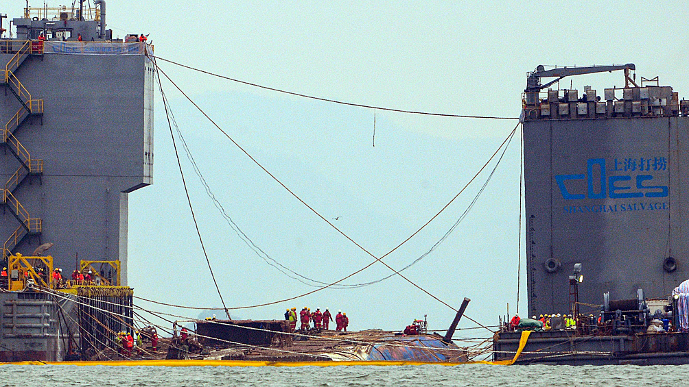 Рабочие стоят на поверхности затонувшего пассажирского парома «Севоль» после его подъема, 2017 год
