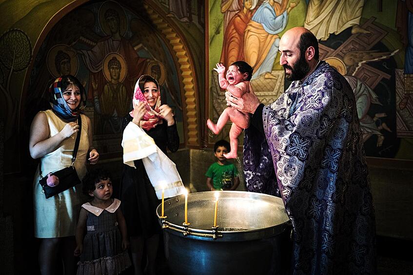Грузинский священник совершает обряд крещения в церкви Тбилиси