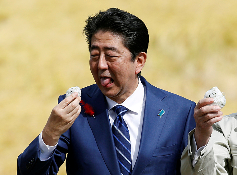 Бывший премьер-министр Японии Синдзо Абэ ест рис, подаренный местными сторонниками во время предвыборного митинга в Фукусиме, 2017 год
