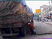 Мотоциклист едва не погиб под колёсами большегруза и попал на видео в Китае
