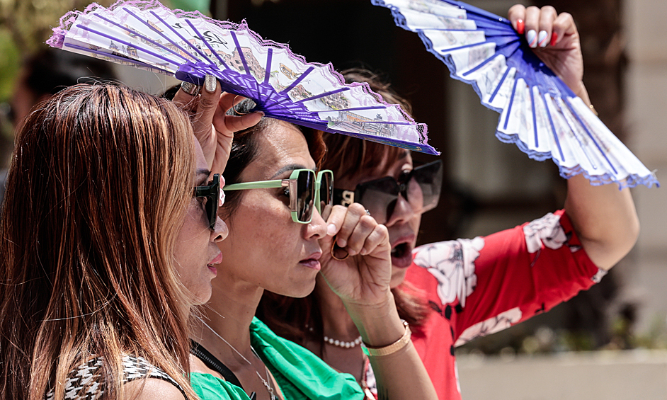 Туристы пытаются защититься от солнца с помощью вееров, Валенсия, Испания