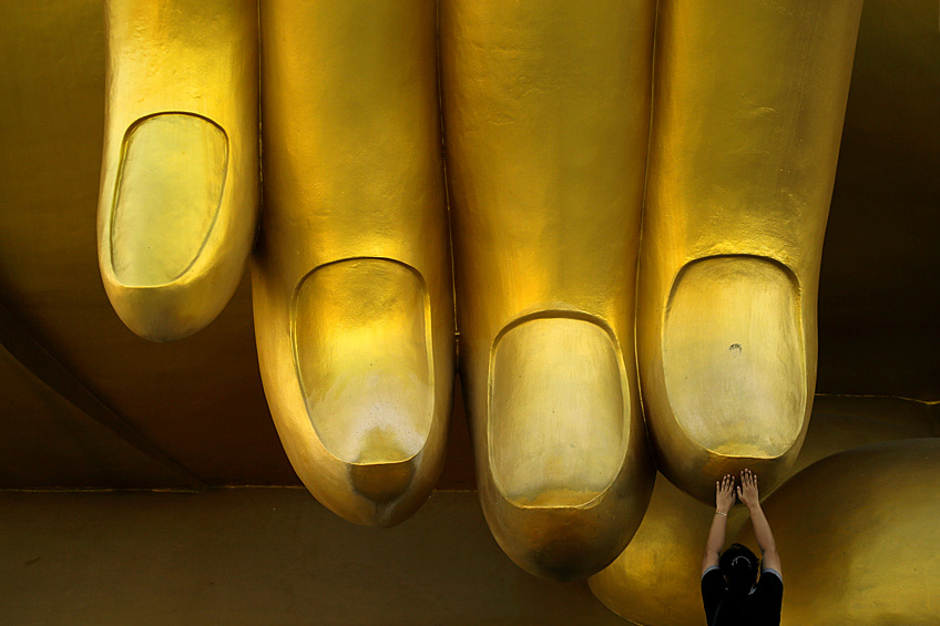 Женщина касается статуи Будды в Ангтхонге, Таиланд
