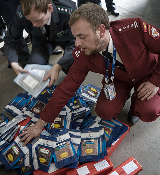 Сотрудник таможенной государственной службы (слева) и сотрудник Роспотребнадзора демонстрирует санкционные продукты, подлежащие уничтожению в инсенераторе на территории аэропорта "Пулково"