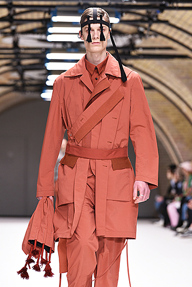 Тренч и брюки работы Крейга Грина выглядели бы вполне конвенционально, если бы не странные аксессуары с кисточками и не самый распространенный в мужском гардеробе терракотовый оттенок.