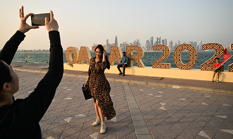 Девушки фотографируются возле стелы "Катар 2022" в Дохе
