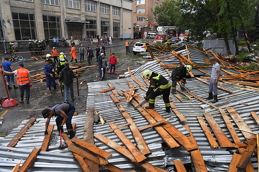 Спасатели убирают фрагменты металлического шифера и деревянных перекрытий обрушившейся из-за сильного ветра части крыши здания на улице Правды.