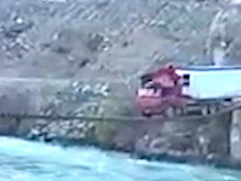 Без права на ошибку: огромный грузовик c домом проехал по узкому мосту над рекой