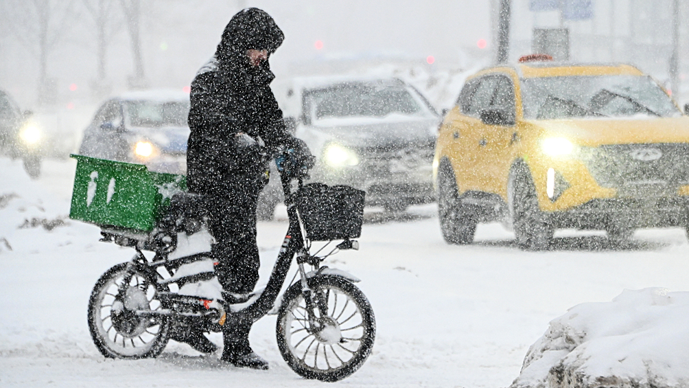  Курьер с велосипедом во время снегопада в Москве