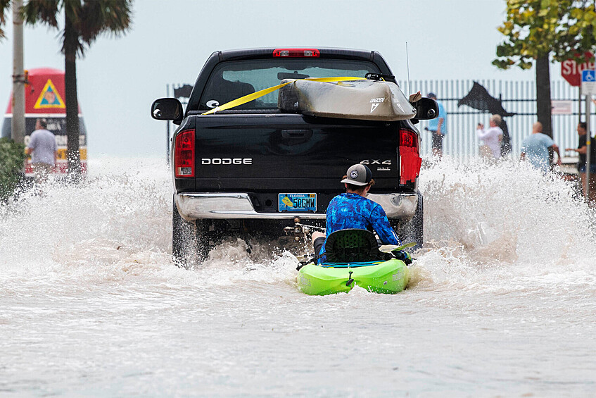 Автомобиль везет человека на байдарке по дороге после наводнения в результате урагана «Иен» в Ки-Уэсте, Флорида, 28 сентября 2022 года