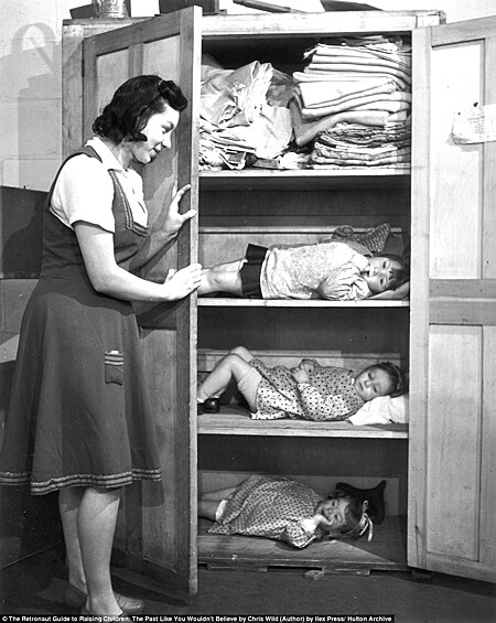 Женщина укрывает детей в шкафу во время немецкого авианалета на Лондон.