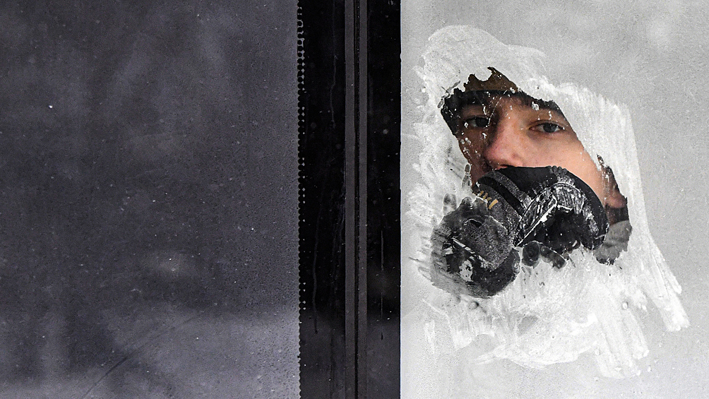 Пассажир смотрит через замороженное окно городского автобуса при температуре воздуха около -27 градусов Цельсия в Красноярске