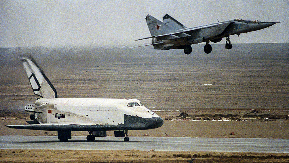 Орбитальный корабль многоразового использования "Буран" и самолет оптико-телевизионного наблюдения (СОТН) МиГ-25 во время посадки на взлетно-посадочную полосу аэродрома "Юбилейный" на космодроме Байконур, 15 ноября 1988 года