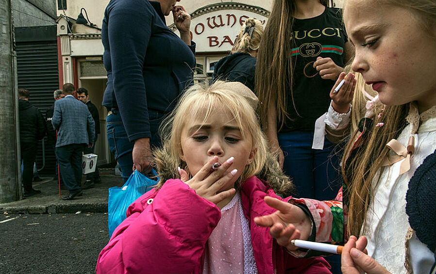  Дети пробуют игрушечные сигареты на ярмарке.