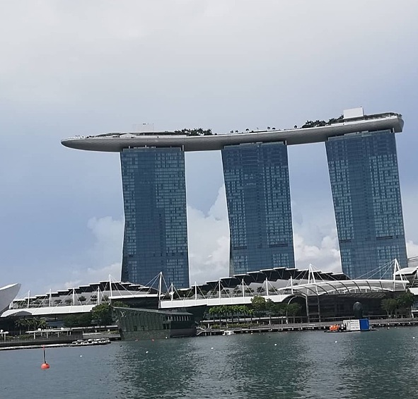 Переносимся в Сингапур. Здание на фото — гостиница Marina Bay Sands. Высота башен — 200 метров, а на них, как земля на трех китах, покоится огромная терраса в виде гондолы. На террасе — бассейн и огромный сад.