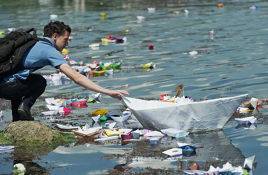 Участник акции "Кораблик Победы" в Феодосии запускает в Черное море бумажный кораблик с именем родственника, воевавшего на фронте Великой Отечественной войны 1941-1945 годов
