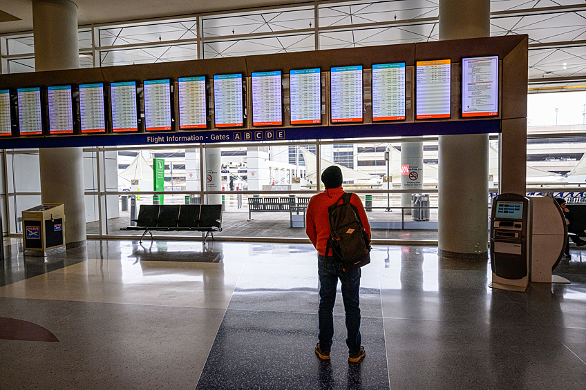 Пассажир смотрит расписание авиарейсов в аэропорту Далласа, штат Техас