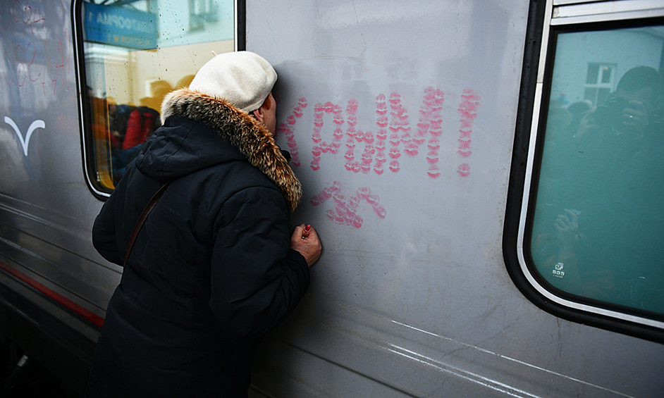 Женщина целует вагон поезда "Таврия", прибывшего на вокзал Севастополя. Поезд первым прошел по Крымскому мосту и возобновил регулярные пассажирские перевозки между материком и полуостровом, которые были прерваны в 2014 году.
