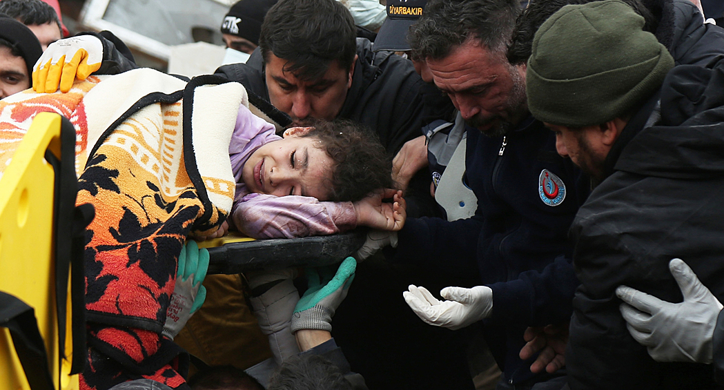 Люди несут девочку, пострадавшую в результате землетрясения в турецком городе Диярбакыр, февраль 2023 года