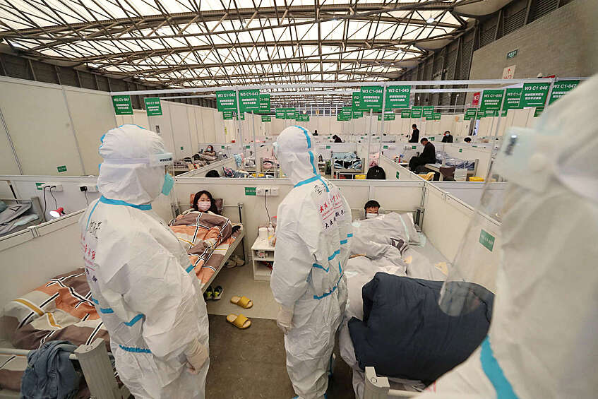 Медицинские работники проводят обход палат в Шанхайском Международном выставочном зале, который был переделан во временную больницу для пациентов с COVID-19, апрель 2022 года