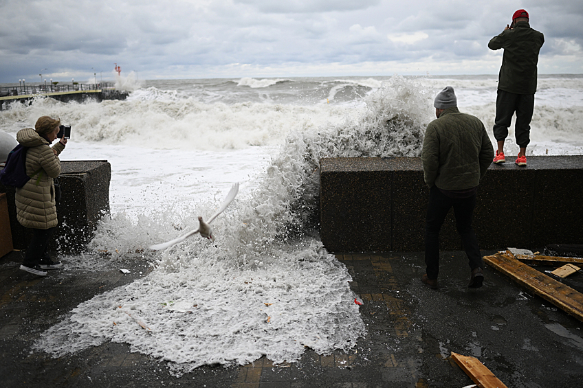 Люди смотрят на шторм на набережной в Сочи, ноябль 2023 года