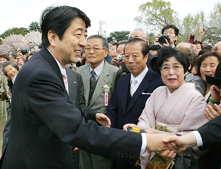 Главный секретарь кабинета министров Японии Синдзо Абэ приветствует гостей во время вечеринки, посвященной цветению сакуры в токийском парке Синдзюку Гёэн, 2006 год
