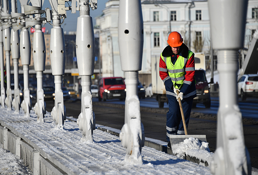 Сотрудник коммунальных служб чистит снег на Крымском мосту в Москве, 16 ноября 2022 года