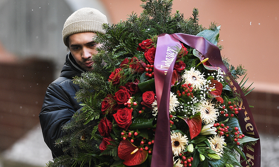Мужчина несет траурный венок на церемонию прощания с народным артистом России Валерием Гаркалиным в учебном центре ГИТИСа в Москве.