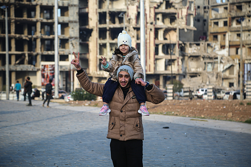Мужчина с ребенком на одной из улиц города Хомс