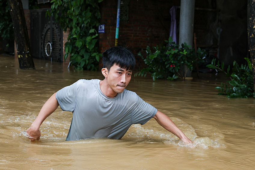 Молодой человек пробирается по затопленной улице в городе Хойане