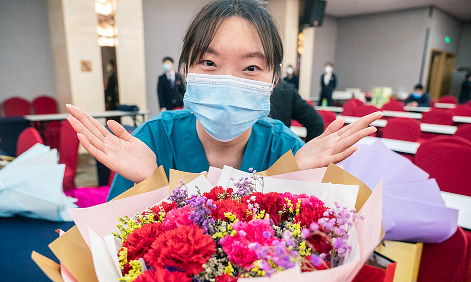 Медицинская сестра с цветами во время пандемии коронавирусной инфекции в Китае, 8 марта 2020 года