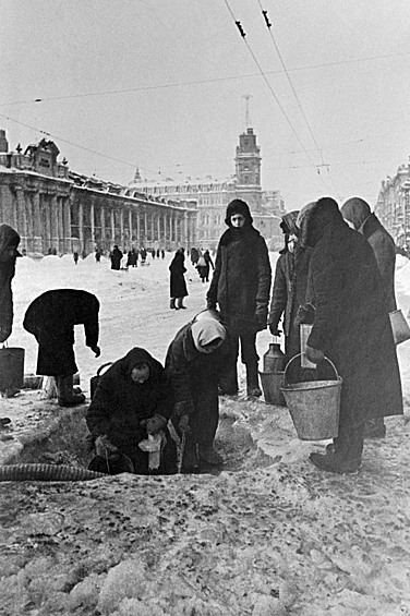 Жители блокадного Ленинграда набирают воду, появившуюся после артобстрела в пробоинах в асфальте на Невском проспекте, 1941 год