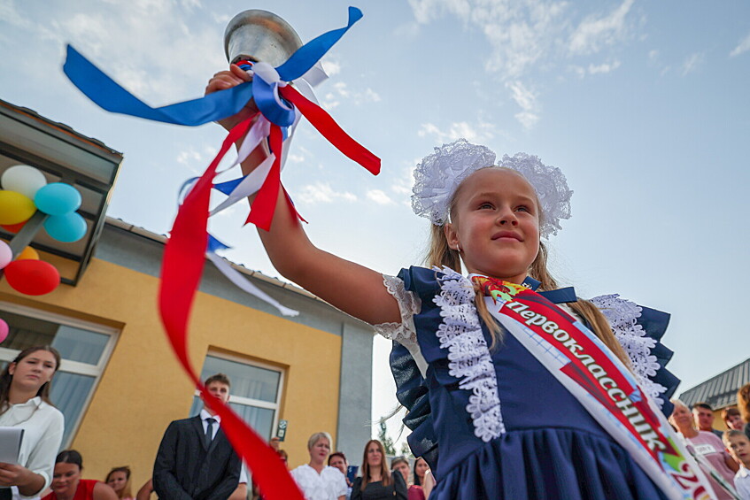 Первоклассница с колокольчиком на праздничной линейке, посвященная Дню знаний в общеобразовательной школе №4 в Геническе, Херсонская область